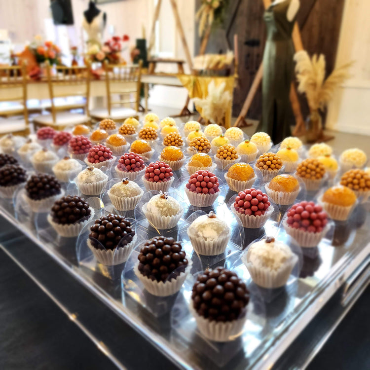 Rows of colorful brigadeiros on a dessert tray